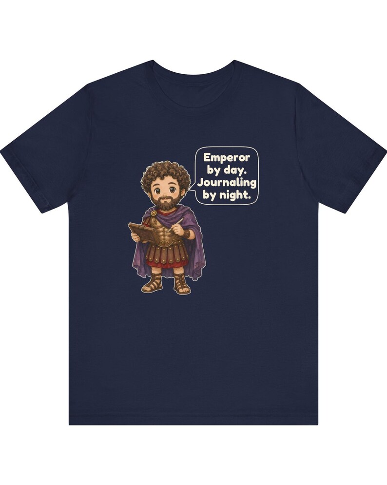 K&ouml;nnte beinhalten: Ein marineblaues T-Shirt mit einer Cartoon-Illustration eines b&auml;rtigen Kaisers in r&ouml;mischer R&uuml;stung und violettem Umhang, der ein Tagebuch und einen Stift h&auml;lt. Eine Sprechblase enth&auml;lt den Text: Emperor by day. Journaling by night.