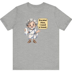 May include: A heather gray t-shirt featuring a cartoon illustration of a bearded figure in a white toga with blue trim, holding a white towel. A yellow speech bubble contains the text: Eureka! Also, I need a towel.