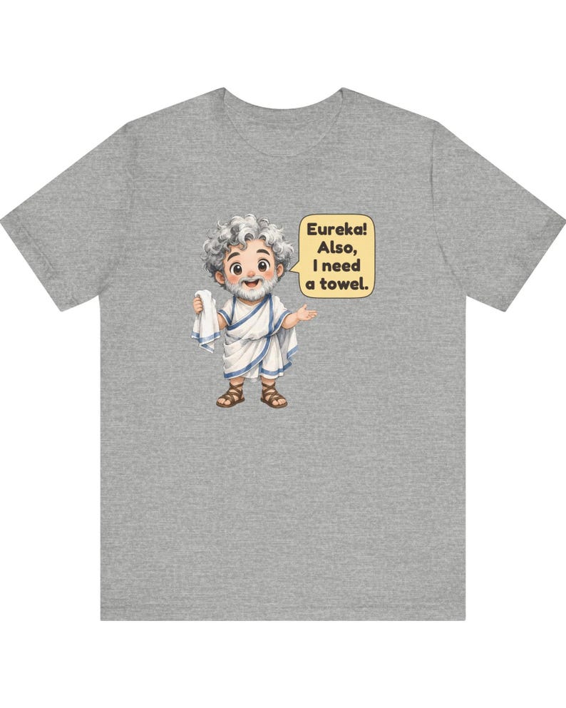 May include: A heather gray t-shirt featuring a cartoon illustration of a bearded figure in a white toga with blue trim, holding a white towel. A yellow speech bubble contains the text: Eureka! Also, I need a towel.