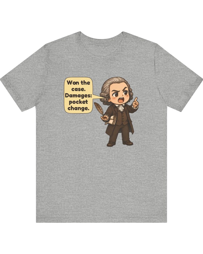 May include: A heather gray t-shirt featuring a cartoon illustration of a lawyer in 18th-century attire holding a quill and a document. A speech bubble contains the text: Won the case. Damages: pocket change.