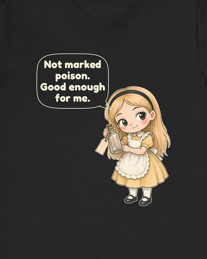 May include: A black t-shirt featuring a cartoon illustration of a blonde character in a yellow dress and white apron holding a glass bottle with a tag. A speech bubble above the character contains the text: Not marked poison. Good enough for me.