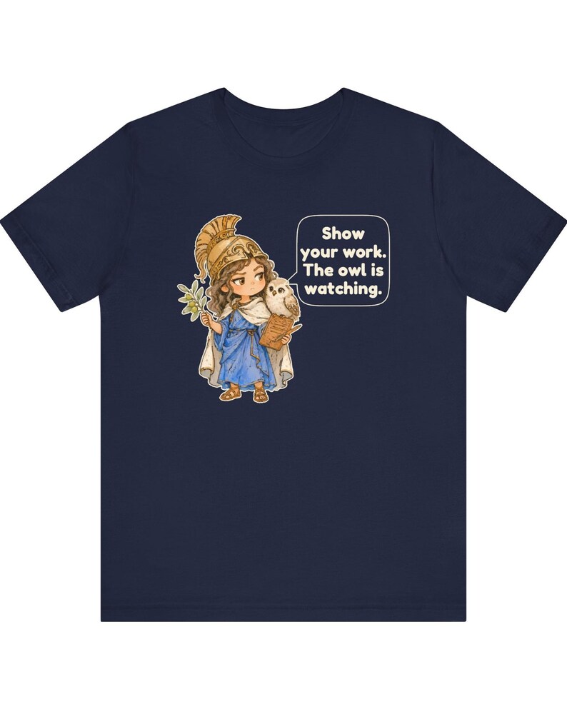 Puede incluir: Una camiseta azul marino con un gr&aacute;fico de un personaje con casco dorado y t&uacute;nica azul, sosteniendo una rama de olivo y un portapapeles con un b&uacute;ho en el hombro. Un bocadillo de di&aacute;logo contiene el texto: Show your work. The owl is watching.