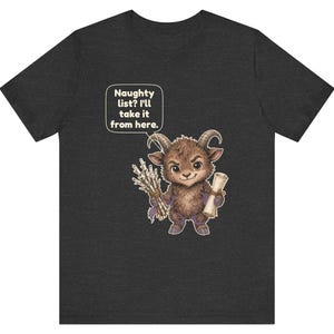 Puede incluir: Una camiseta de manga corta gris oscuro con el gr&aacute;fico de una criatura marr&oacute;n con cuernos que sostiene un manojo de palos y un pergamino. Un globo de texto sobre la criatura contiene el texto: Naughty list? I'll take it from here.