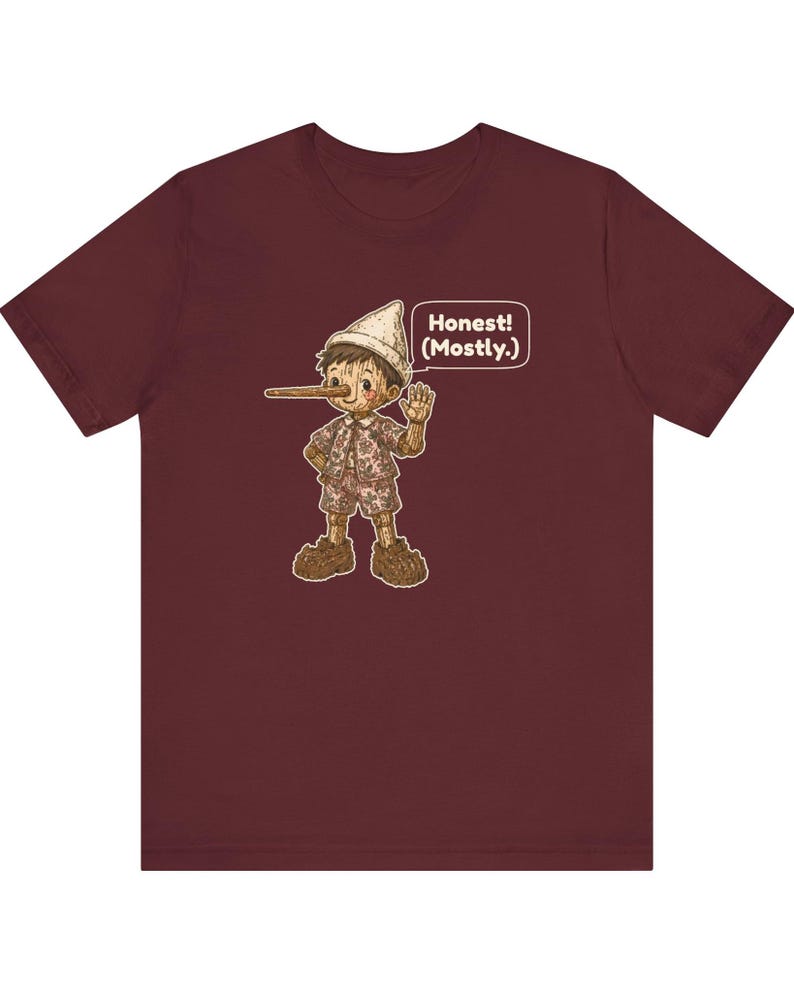K&ouml;nnte beinhalten: Ein bordeauxrotes Kurzarm-T-Shirt mit einer Grafik einer Holzpuppe mit langer Nase, die einen Hut, ein Hemd und eine kurze Hose tr&auml;gt. Die Figur winkt und eine Sprechblase neben ihr enth&auml;lt den Text, Honest! (Mostly.)