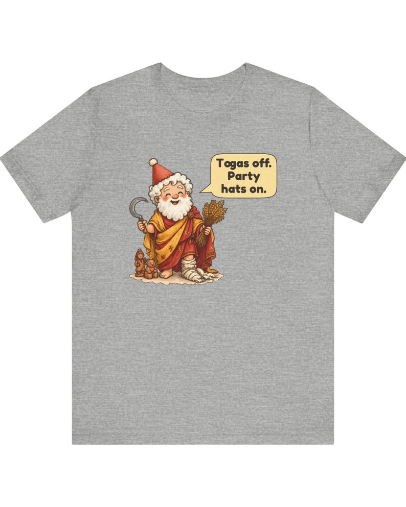 May include: A heather gray t-shirt featuring a cartoon illustration of a bearded figure in a red and yellow robe, holding a sickle and wheat. A speech bubble contains the text: Togas off. Party hats on. The figure wears a red party hat.