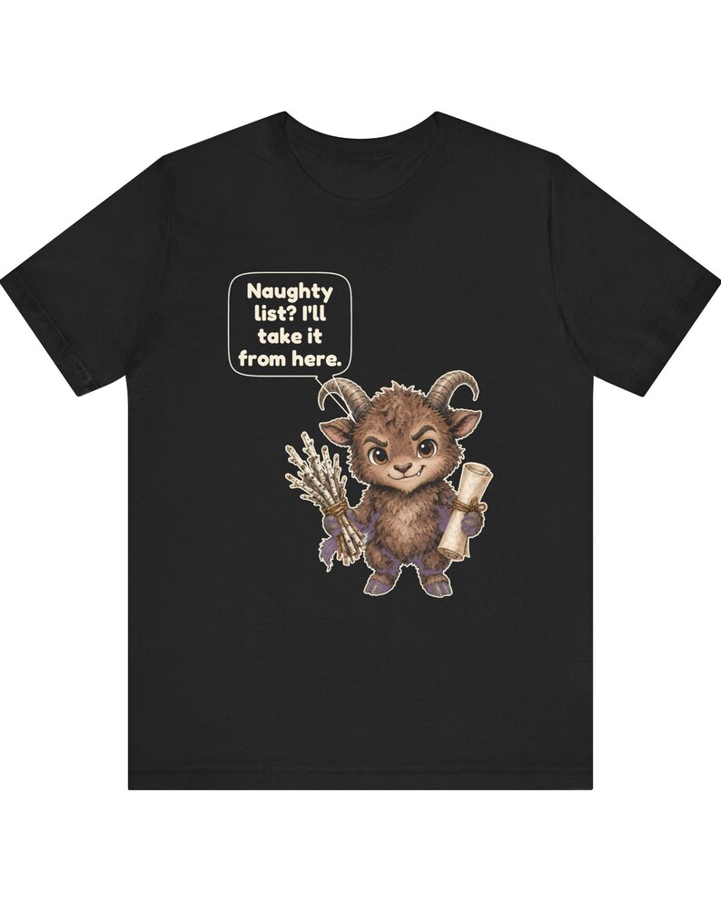 Puede incluir: Una camiseta negra con el gr&aacute;fico de una criatura marr&oacute;n, peluda y con cuernos que sostiene un manojo de palos y un pergamino. Un globo de texto sobre la criatura contiene el texto: Naughty list? I'll take it from here.