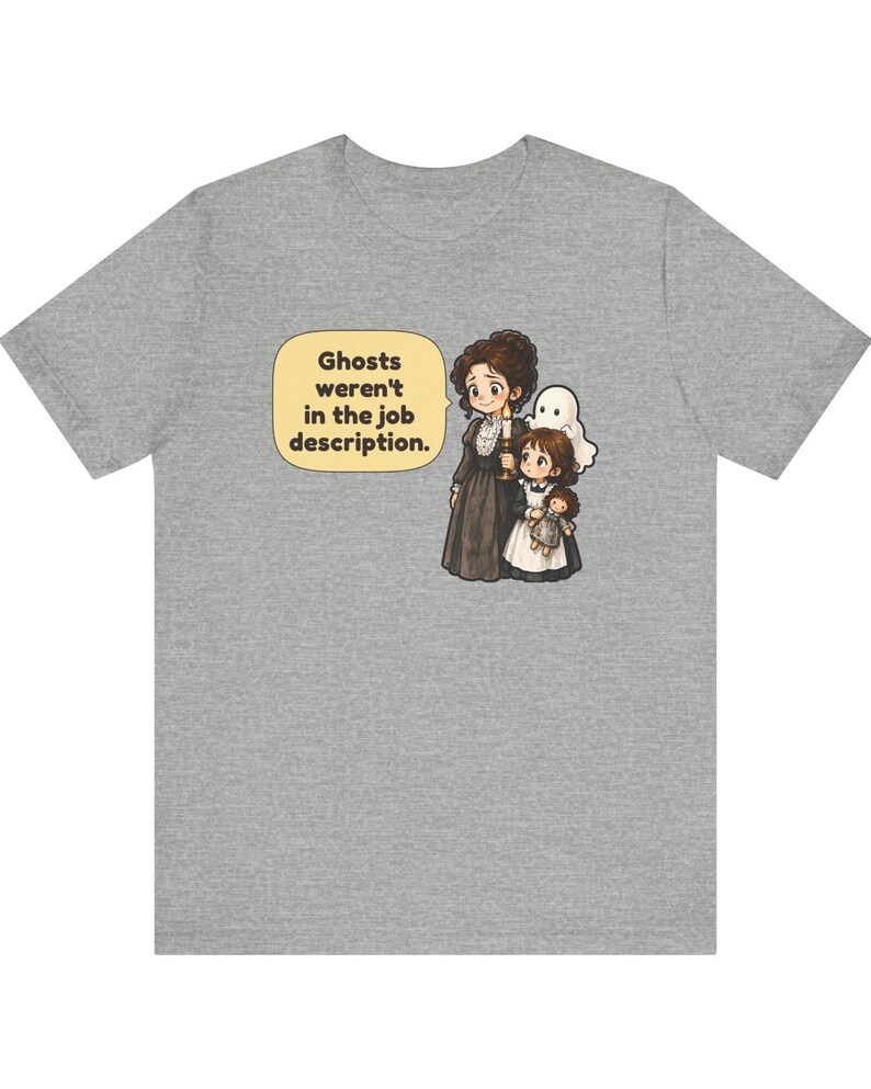 Op de afbeelding: Een grijs gem&ecirc;leerd t-shirt met een cartoonillustratie van een persoon in een donkere jurk die een kaars vasthoudt en een kind met een pop, met een klein wit spookje erachter. Een tekstballon bevat de tekst: Ghosts weren't in the job description.