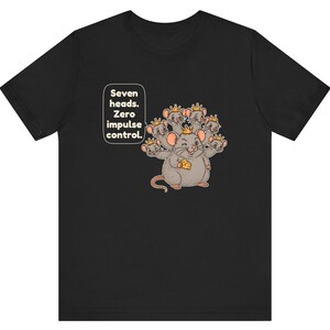 May include: A black short-sleeved t-shirt featuring a graphic of a gray seven-headed rat wearing small gold crowns. The rat holds a piece of yellow cheese. Text in a white speech bubble reads: Seven heads. Zero impulse control.