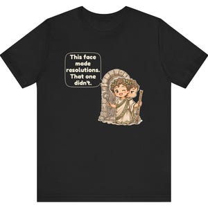 K&ouml;nnte beinhalten: Ein schwarzes T-Shirt mit einer Grafik einer r&ouml;mischen Figur mit zwei Gesichtern, die einen Lorbeerkranz tr&auml;gt und einen Schl&uuml;ssel sowie einen Stab vor einem Torbogen h&auml;lt. Eine Sprechblase enth&auml;lt den Text: This face made resolutions. That one didn't.