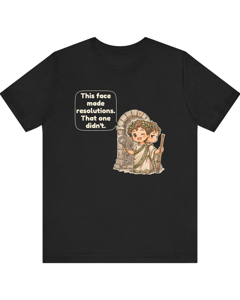 K&ouml;nnte beinhalten: Ein schwarzes T-Shirt mit einer Grafik einer r&ouml;mischen Figur mit zwei Gesichtern, die einen Lorbeerkranz tr&auml;gt und einen Schl&uuml;ssel sowie einen Stab vor einem Torbogen h&auml;lt. Eine Sprechblase enth&auml;lt den Text: This face made resolutions. That one didn't.