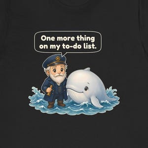 May include: A black t-shirt featuring a graphic of a cartoon sea captain with a white beard and a blue uniform standing next to a white whale in blue water. A speech bubble above the captain contains the text, One more thing on my to-do list.