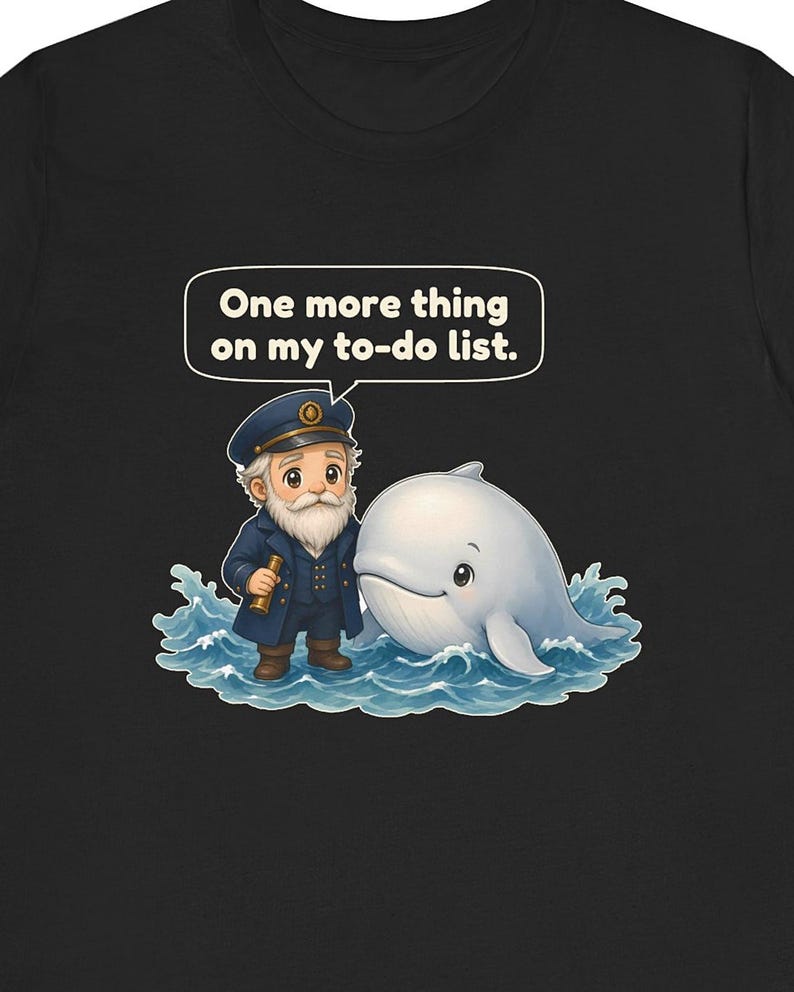 May include: A black t-shirt featuring a graphic of a cartoon sea captain with a white beard and a blue uniform standing next to a white whale in blue water. A speech bubble above the captain contains the text, One more thing on my to-do list.