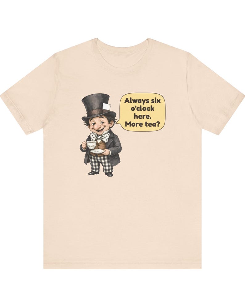 May include: A light beige t-shirt featuring a graphic of a character wearing a top hat, a brown vest, and a polka-dot bow tie, holding a teacup. A yellow speech bubble contains the text: Always six o'clock here. More tea?