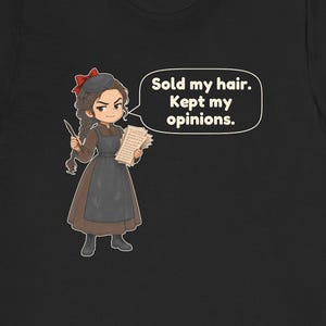 May include: A black t-shirt featuring a cartoon illustration of a person with braided hair, a red bow, and a brown dress with a dark apron. The character holds a quill and papers, with a speech bubble containing the text: Sold my hair. Kept my opinions.