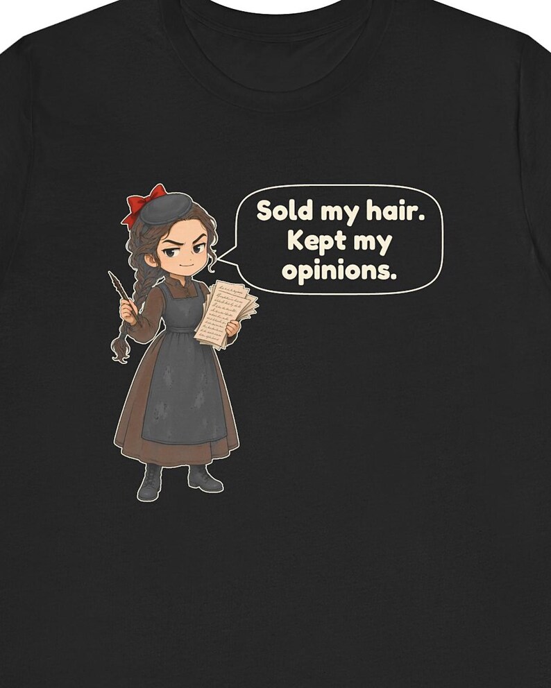 May include: A black t-shirt featuring a cartoon illustration of a person with braided hair, a red bow, and a brown dress with a dark apron. The character holds a quill and papers, with a speech bubble containing the text: Sold my hair. Kept my opinions.