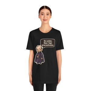May include: A black short-sleeved t-shirt featuring a cartoon illustration of a bearded figure in a purple robe holding a book and sword. A speech bubble above the figure contains the text: Ex-soldier. Now I fight procrastination.