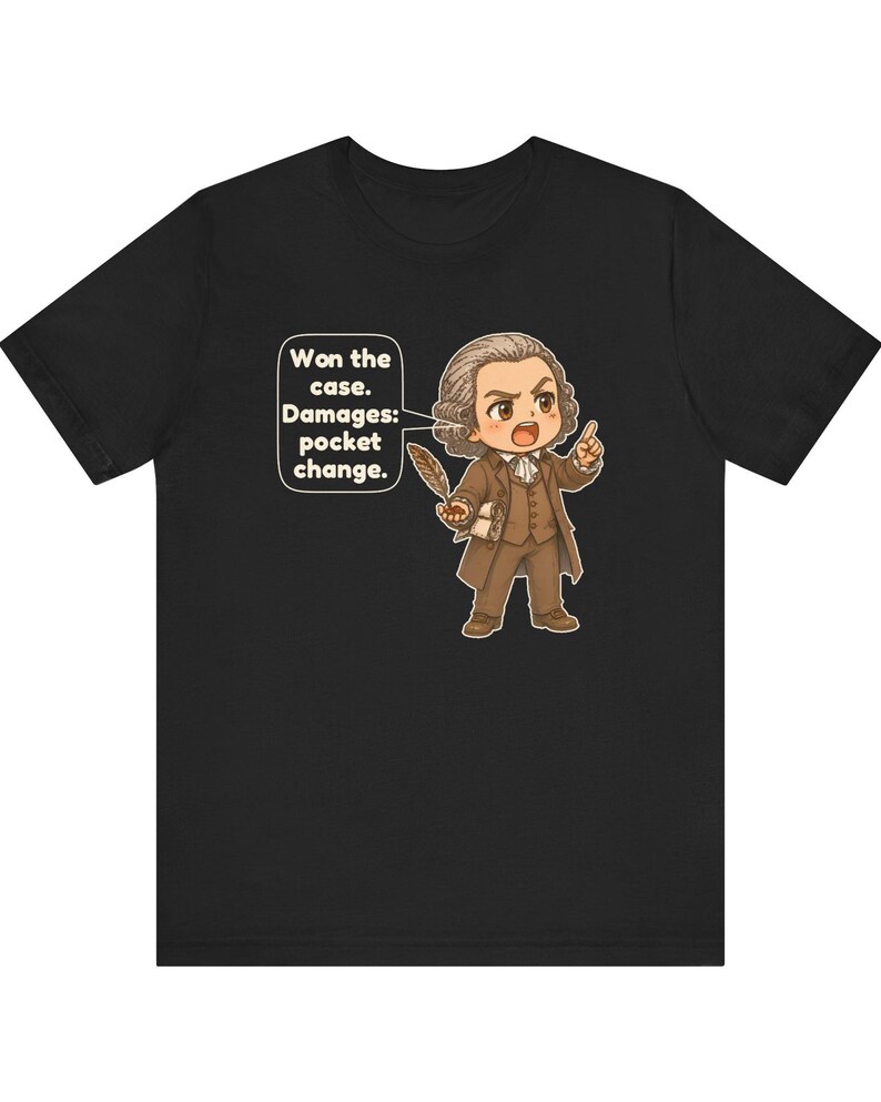 May include: A black t-shirt featuring a cartoon illustration of a historical figure in a brown suit holding a quill. A speech bubble contains the text: Won the case. Damages: pocket change. The character has a powdered wig and an expressive face.