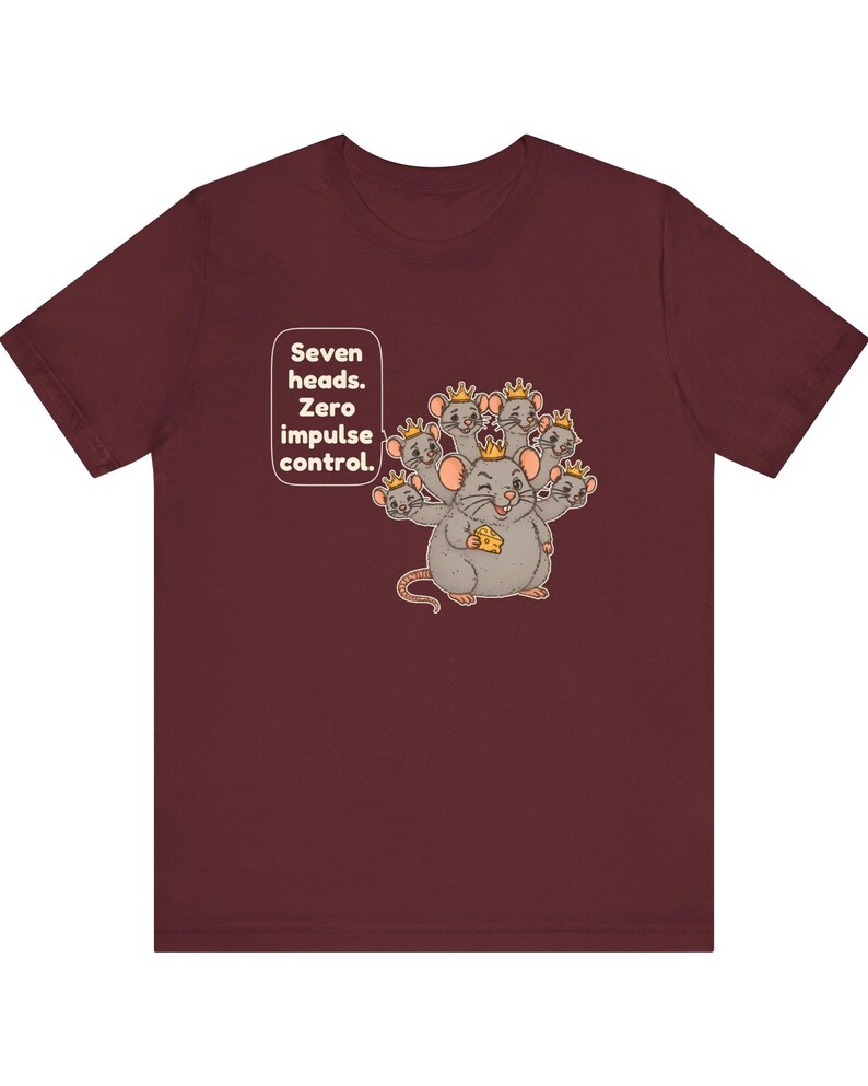 May include: A maroon short-sleeve t-shirt featuring a graphic of a seven-headed mouse wearing small gold crowns and holding a piece of yellow cheese. The text "Seven heads. Zero impulse control." is printed in a white speech bubble.