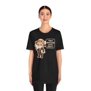 Puede incluir: Una camiseta negra con una ilustraci&oacute;n de dibujos animados de un artista mayor con barba blanca, que lleva un sombrero de paja con flores, sostiene un pincel y una paleta, con un bocadillo que dice: Dug a whole pond just to paint it.