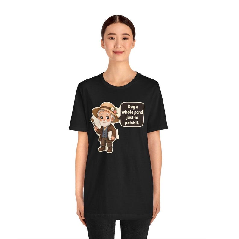 Puede incluir: Una camiseta negra con una ilustraci&oacute;n de dibujos animados de un artista mayor con barba blanca, que lleva un sombrero de paja con flores, sostiene un pincel y una paleta, con un bocadillo que dice: Dug a whole pond just to paint it.