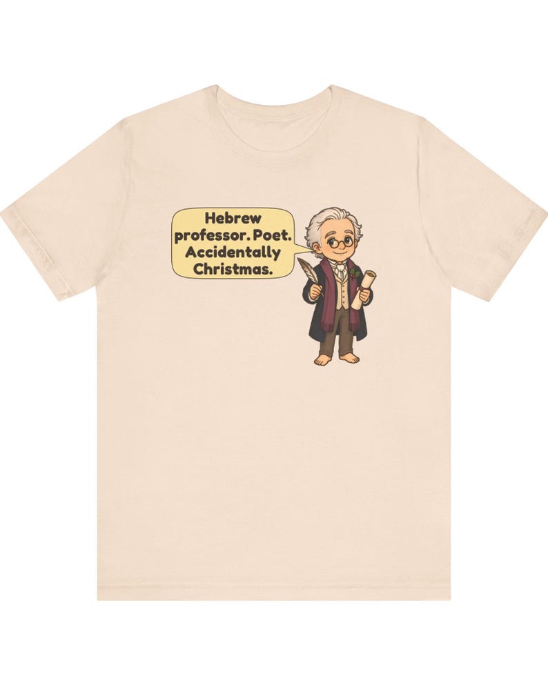 Pu&ograve; includere: Una t-shirt beige chiaro con un'illustrazione a cartone animato di una persona con capelli grigi, occhiali e un cappotto scuro che tiene in mano una penna e una pergamena. Un fumetto giallo contiene il testo: Hebrew professor. Poet. Accidentally Christmas.