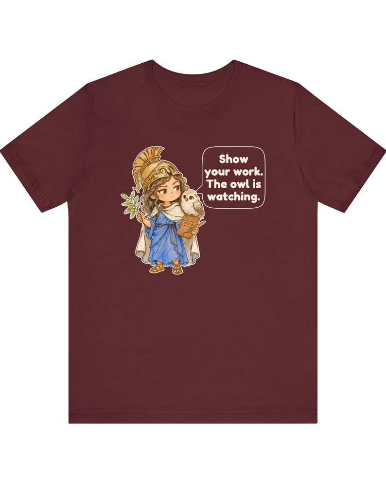 Puede incluir: Una camiseta de manga corta color granate con el gr&aacute;fico de un personaje con casco dorado y t&uacute;nica azul, sosteniendo una rama de olivo y un b&uacute;ho. Un bocadillo de texto incluye: Show your work. The owl is watching.