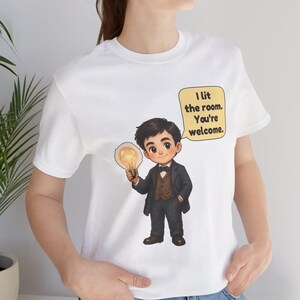 Może przedstawiać: Biały t-shirt z rysunkową ilustracją osoby w ciemnym garniturze i muszce, trzymającej świecącą żar&oacute;wkę. Dymek obok postaci zawiera tekst: I lit the room. You're welcome.