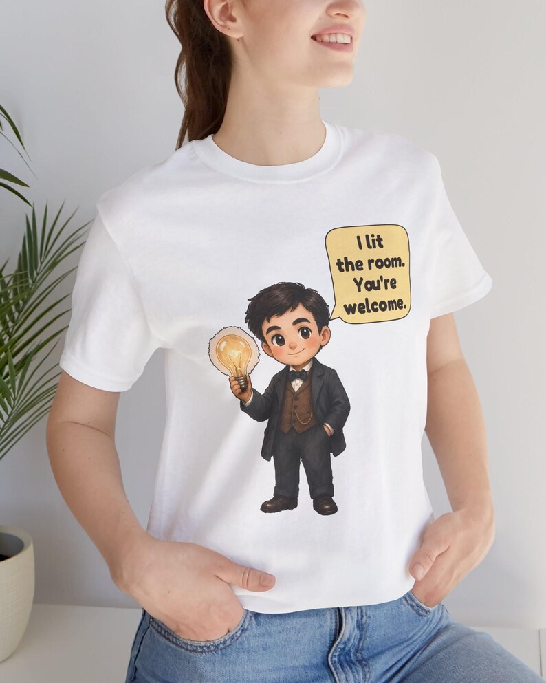 Może przedstawiać: Biały t-shirt z rysunkową ilustracją osoby w ciemnym garniturze i muszce, trzymającej świecącą żar&oacute;wkę. Dymek obok postaci zawiera tekst: I lit the room. You're welcome.
