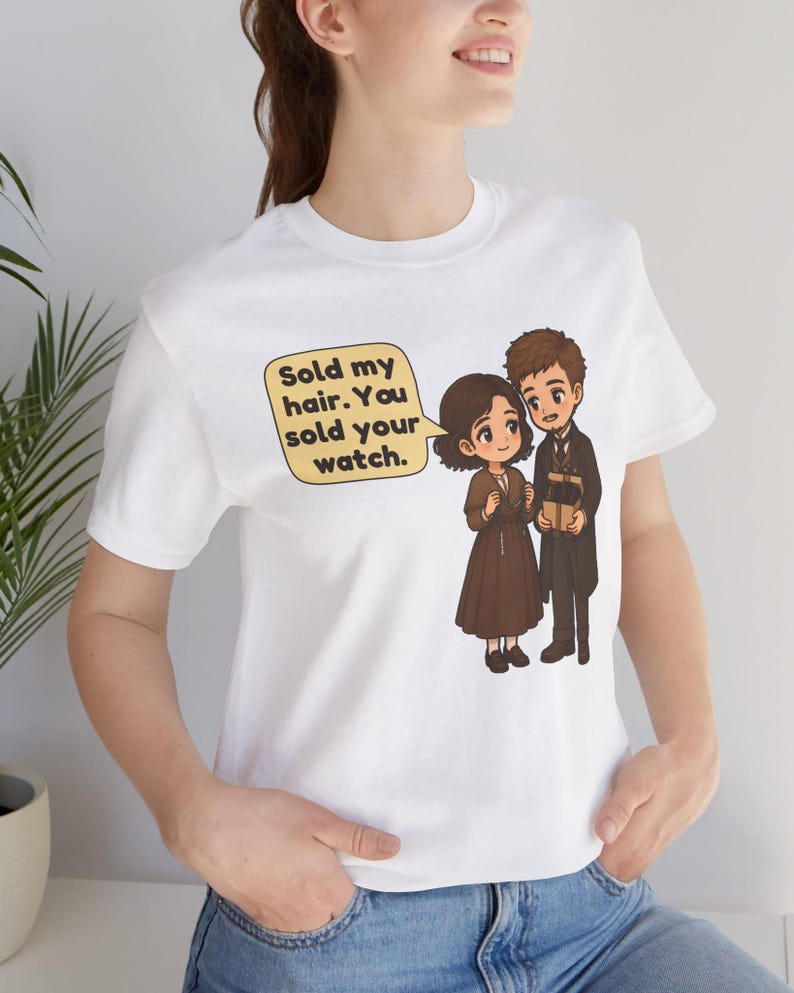 May include: A white t-shirt featuring a cartoon illustration of two figures. One figure wears a brown dress, the other a dark coat. A speech bubble contains the text: Sold my hair. You sold your watch. The design is centered on the chest area.