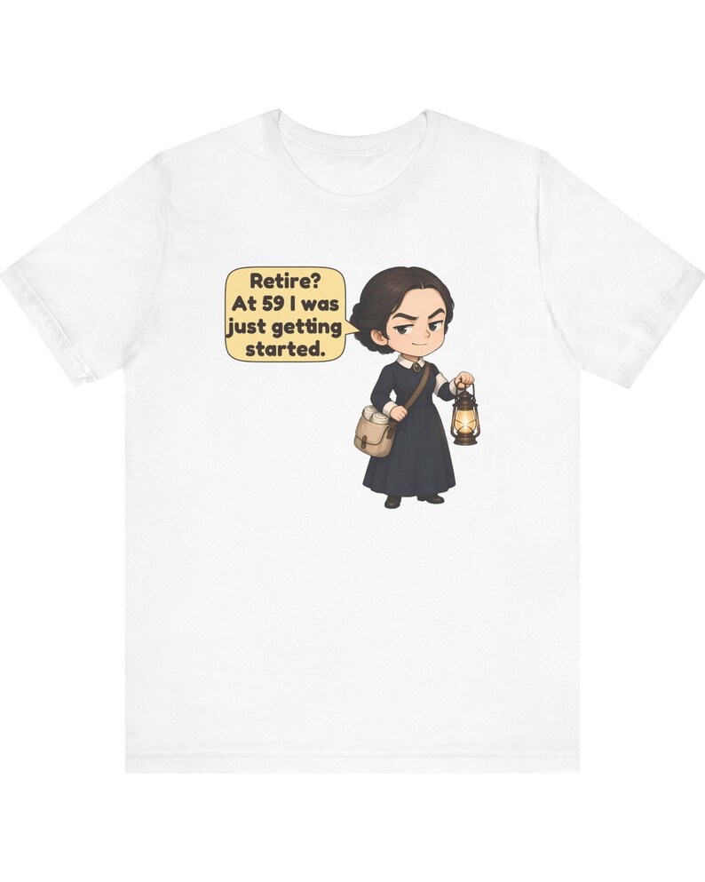 May include: A white t-shirt featuring a cartoon illustration of a person with dark hair wearing a long black dress, carrying a tan satchel and a lit lantern. A yellow speech bubble contains the text: Retire? At 59 I was just getting started.