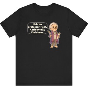 Pu&ograve; includere: Una t-shirt nera con un'illustrazione a cartoni animati di una persona con capelli bianchi, occhiali e cappotto viola, che tiene in mano una penna e una pergamena. Un fumetto contiene il testo: Hebrew professor. Poet. Accidentally Christmas.