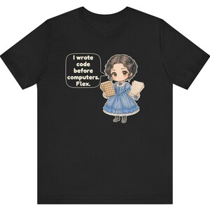 May include: A black t-shirt featuring a cartoon illustration of a person in a blue Victorian-style dress holding punch cards and papers. A speech bubble next to the character contains the text: I wrote code before computers. Flex.