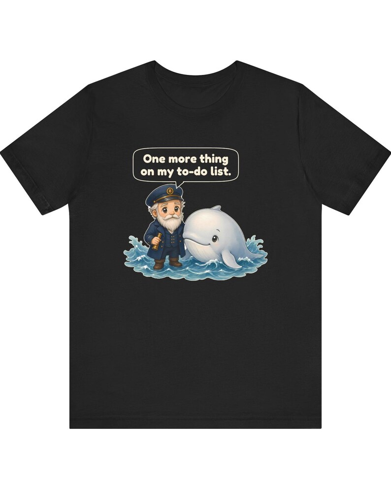 May include: A black t-shirt featuring a graphic of a sea captain with a white beard and a white whale in blue ocean waves. Above the captain is a speech bubble with the text, One more thing on my to-do list. The design is centered on the chest.