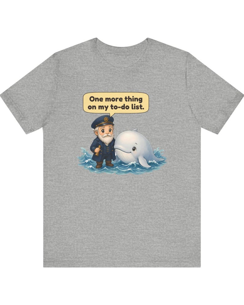 May include: A heather gray t-shirt featuring a graphic of a cartoon sea captain with a white beard and a white whale in blue ocean waves. A yellow speech bubble above them contains the black text, One more thing on my to-do list.