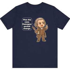 May include: A navy blue t-shirt featuring a cartoon illustration of a historical figure in a brown suit holding a quill. A speech bubble contains the text: Won the case. Damages: pocket change. The figure has brown hair and is pointing.