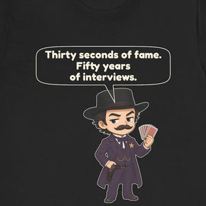 Pu&ograve; includere: Una t-shirt nera con un'illustrazione in stile cartoon di una persona con i baffi che indossa un abito scuro, un cappello e una stella da sceriffo. Il personaggio tiene in mano delle carte da gioco. Sopra c'&egrave; un fumetto con il testo: Thirty seconds of fame. Fifty years of interviews.