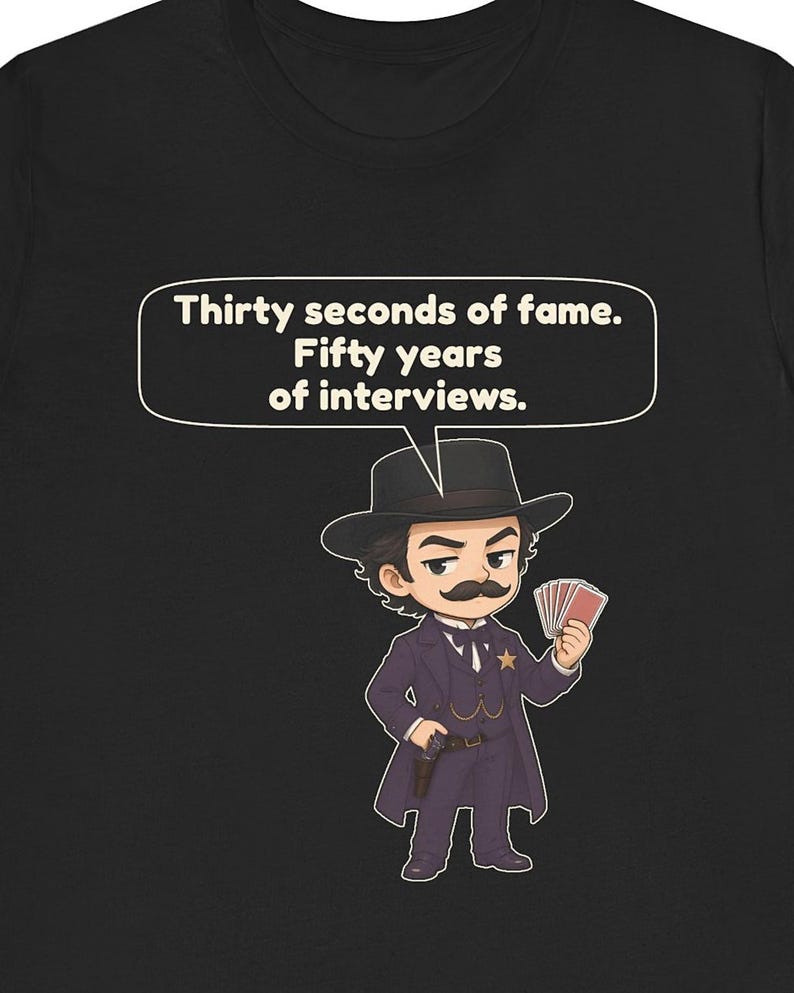 Pu&ograve; includere: Una t-shirt nera con un'illustrazione in stile cartoon di una persona con i baffi che indossa un abito scuro, un cappello e una stella da sceriffo. Il personaggio tiene in mano delle carte da gioco. Sopra c'&egrave; un fumetto con il testo: Thirty seconds of fame. Fifty years of interviews.