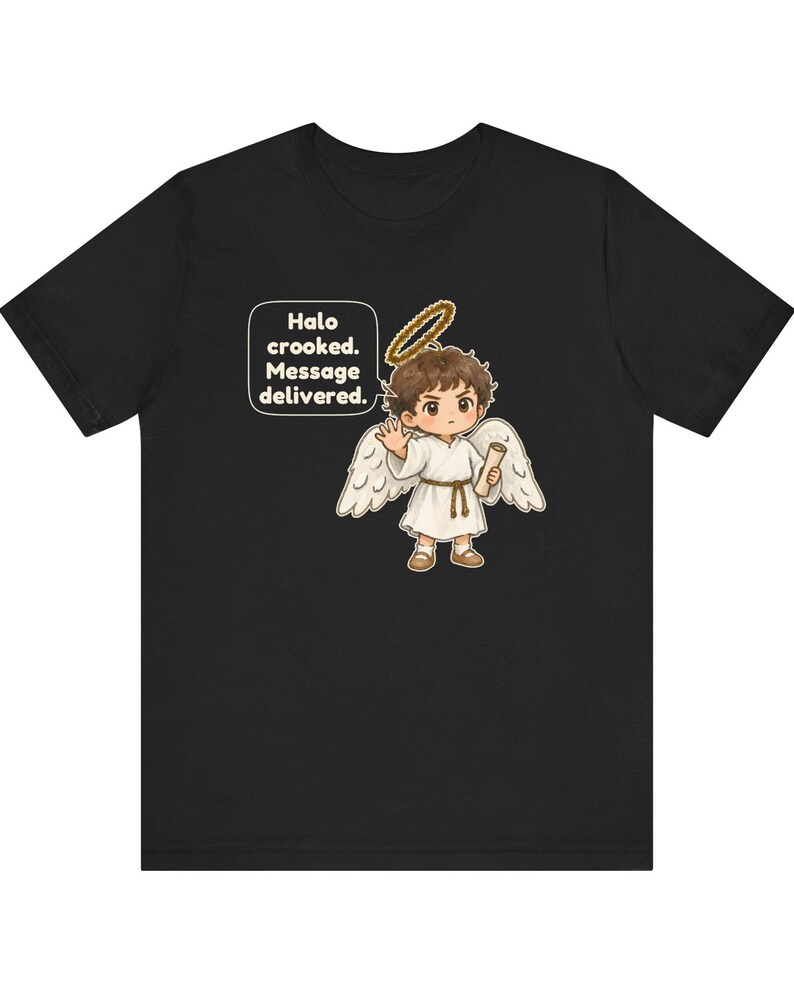 May include: A black t-shirt featuring a cartoon angel with brown hair, white wings, and a golden halo. The angel wears a white robe with a brown belt and holds a scroll. A speech bubble contains the text: Halo crooked. Message delivered.
