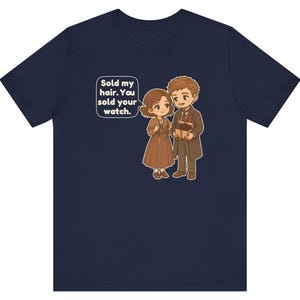 May include: A navy blue t-shirt featuring a cartoon illustration of two people in brown clothing. A speech bubble contains the text: Sold my hair. You sold your watch. The characters are depicted in a chibi style with brown hair and brown outfits.