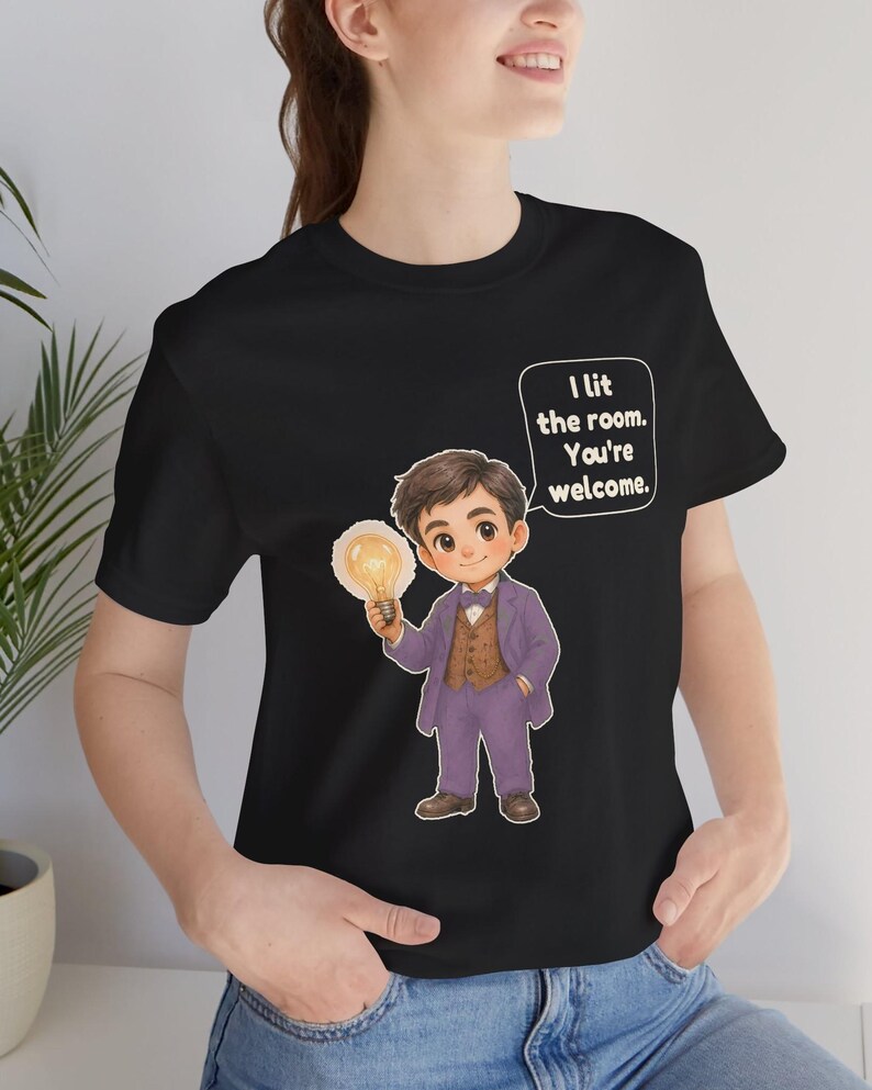 Może przedstawiać: Czarny t-shirt z rysunkową ilustracją osoby w fioletowym garniturze i brązowej kamizelce, trzymającej świecącą żar&oacute;wkę. Dymek z tekstem zawiera napis: I lit the room. You're welcome.