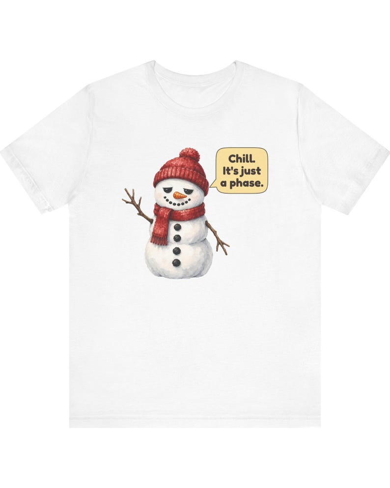 Pode incluir: Uma t-shirt branca com um gr&aacute;fico de um boneco de neve a usar um gorro e um cachecol de malha vermelhos. O boneco de neve tem bra&ccedil;os de pau, um nariz de cenoura e bot&otilde;es pretos. Um bal&atilde;o de fala amarelo cont&eacute;m o texto, Chill. It's just a phase.
