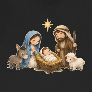 May include: A black t-shirt featuring a graphic of a nativity scene with a baby in a manger, a person in a blue head covering, a person in a brown robe with a staff, a donkey, a white sheep, and a yellow star against a dark background.