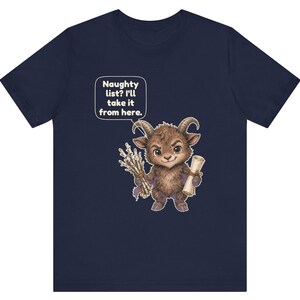 Puede incluir: Una camiseta azul marino de manga corta con el gr&aacute;fico de una criatura marr&oacute;n con cuernos que sostiene un manojo de ramas y un pergamino. Un globo de texto sobre la criatura contiene el texto: Naughty list? I'll take it from here.