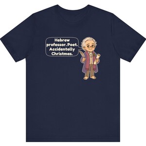 Pu&ograve; includere: Una t-shirt a maniche corte blu navy con un'illustrazione a cartone animato di un uomo con gli occhiali che tiene in mano una penna e una pergamena. Un fumetto accanto al personaggio contiene il testo: Hebrew professor. Poet. Accidentally Christmas.