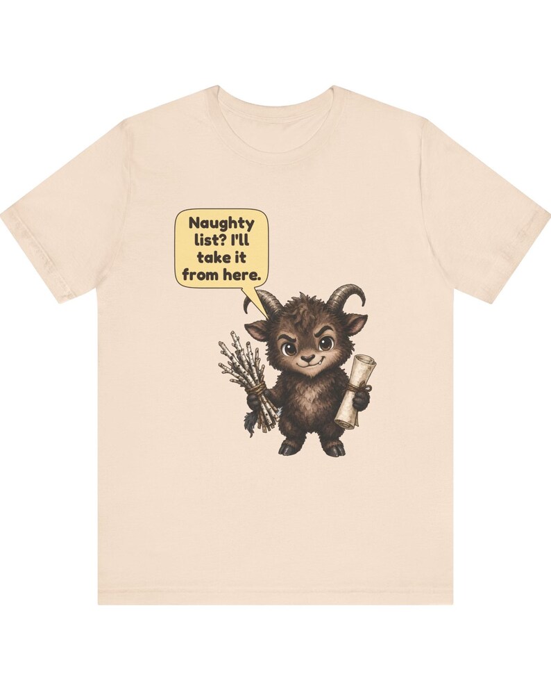 Puede incluir: Una camiseta de color beige claro con el gr&aacute;fico de una peque&ntilde;a criatura marr&oacute;n oscura con cuernos que sostiene un manojo de palos y un pergamino. Un globo de texto amarillo sobre la criatura contiene: Naughty list? I'll take it from here.