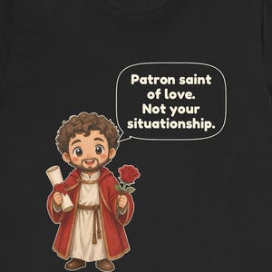 Puede incluir: Una camiseta negra con una ilustraci&oacute;n de dibujos animados de una figura barbuda con t&uacute;nica roja que sostiene un pergamino y una rosa roja. Un bocadillo contiene el texto: Patron saint of love. Not your situationship. El dise&ntilde;o est&aacute; centrado.