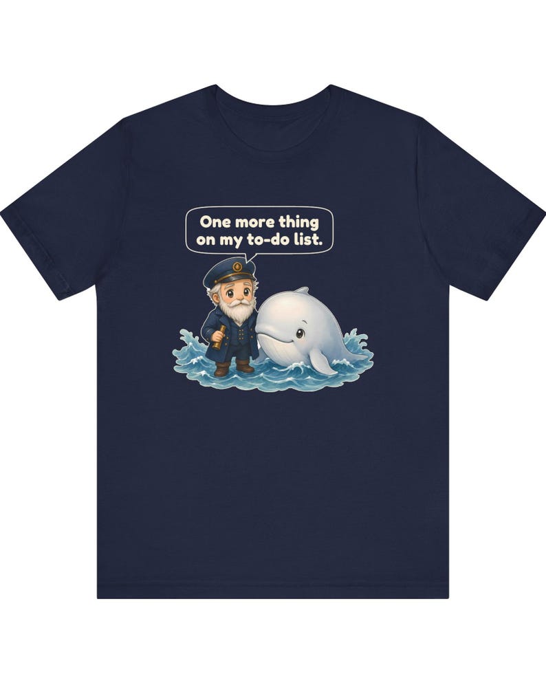 May include: A navy blue t-shirt featuring a graphic of a bearded sea captain in a uniform holding a telescope next to a white whale in blue ocean waves. A speech bubble above them contains the text: One more thing on my to-do list.