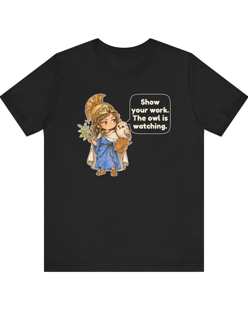 Puede incluir: Una camiseta negra con un gr&aacute;fico de un personaje con casco dorado y t&uacute;nica azul, sosteniendo una rama de olivo y un portapapeles con un b&uacute;ho en el hombro. Un globo de texto contiene: Show your work. The owl is watching.