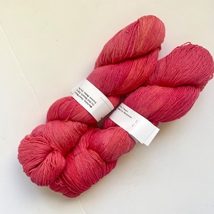 May include: Two skeins of pink yarn with white labels that read "Machine, Hand Wash Do Not Bleach. Remove Excess Water. Dry Flat" and "Dry Clean.  Attached to Remove".