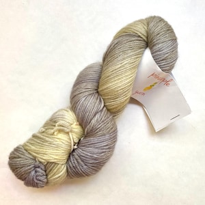 May include: A skein of yarn in a light gray and yellow colorway. The yarn is labeled "pineapple yarn".